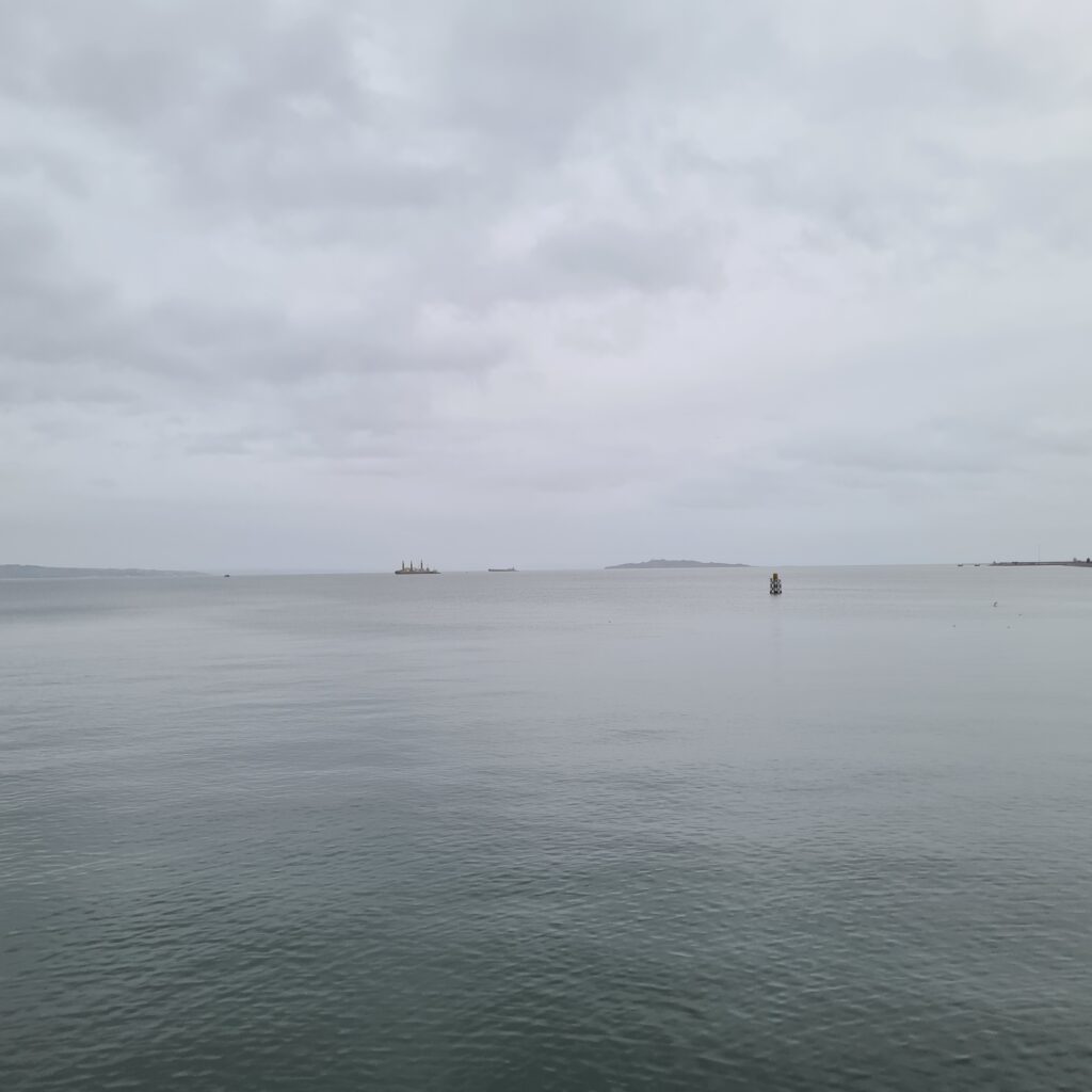 Photo of a flat grey sea under a cloudy grey sky